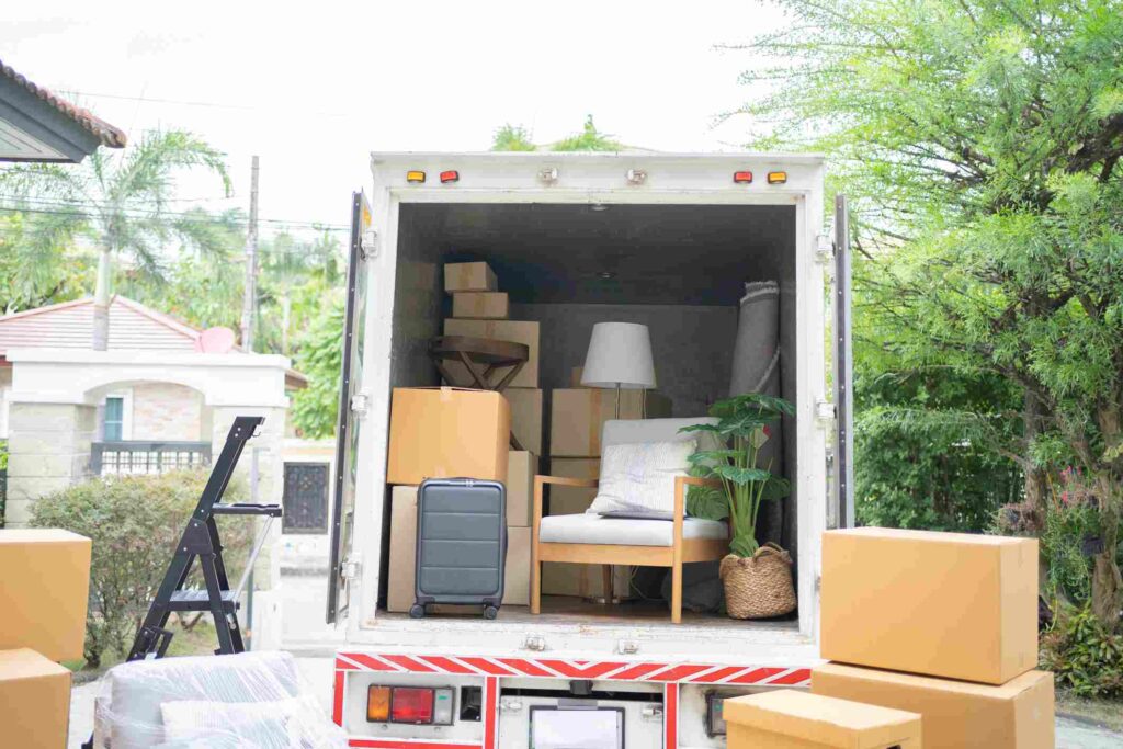 Furniture pieces and boxes arranged inside and outside of a moving truck.