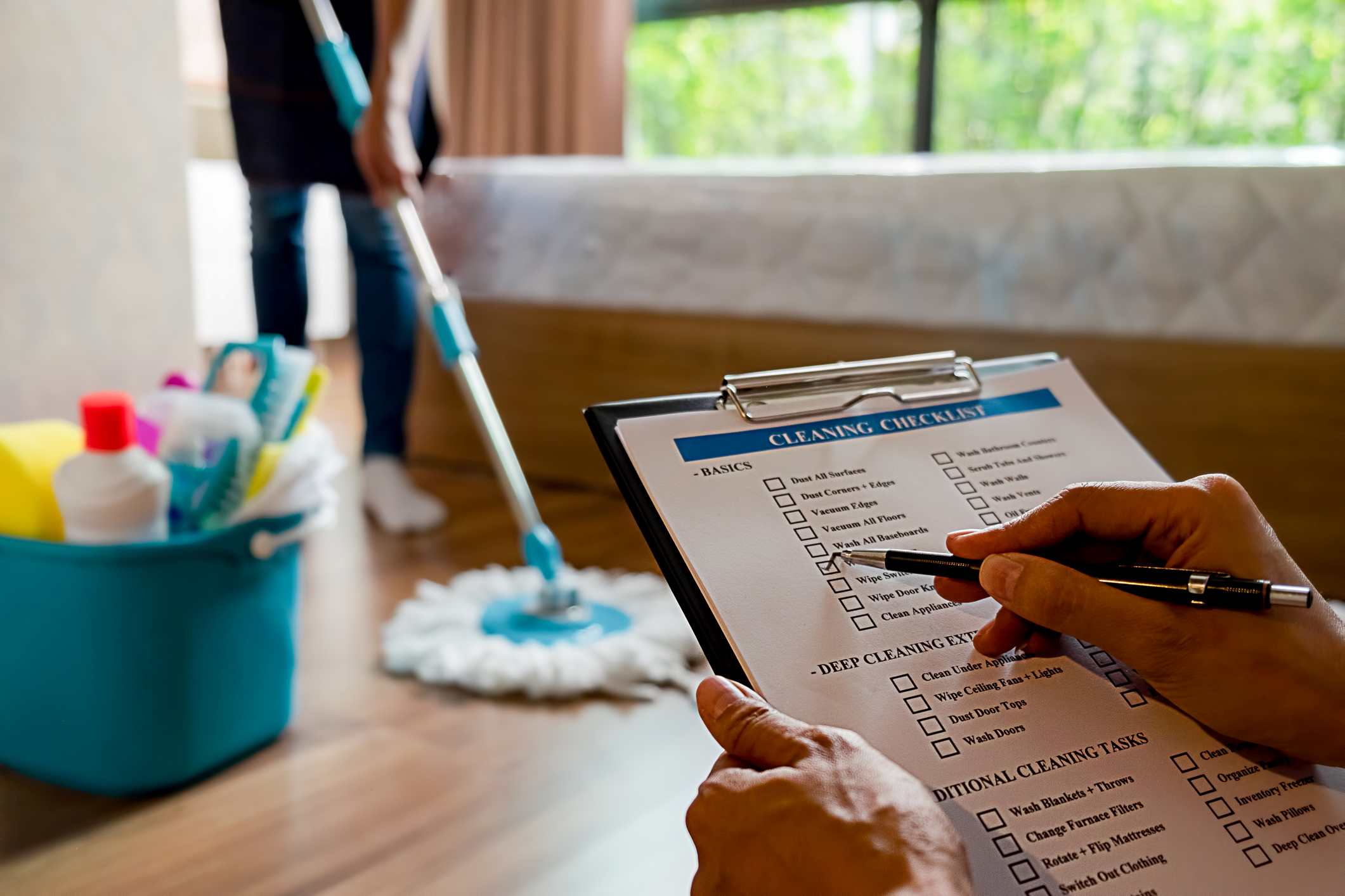 A person checks items off a to-do list for cleaning their home.